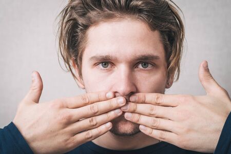 The man closed his mouth with her hands.の写真素材