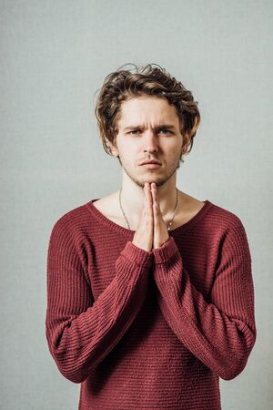 A man prays. On a gray background.