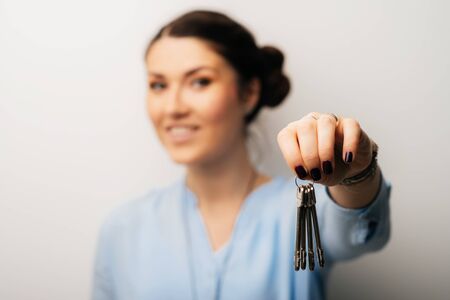 Pretty brunette girl holding keys in his handの写真素材