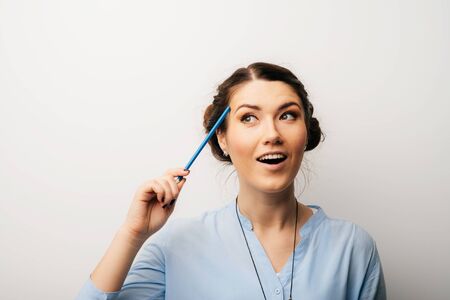 Pretty brunette girl thinking holding a pencil at a templeの写真素材