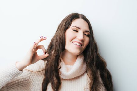 on a white background young girl with long hair shows OKの写真素材