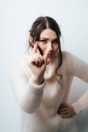 Brunette girl shows something very small on a white backgroundの写真素材