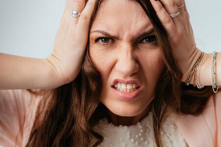 long-haired beautiful brunette girl angry and holding his head isolated on white background