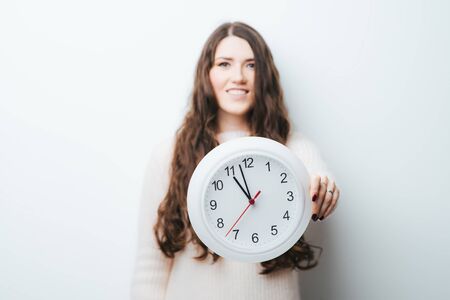 on a white background girl holding a clock in his hands