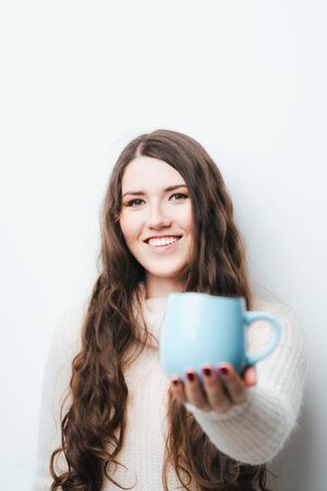 brunette girl drinking coffee or tea on a white backgroundの写真素材