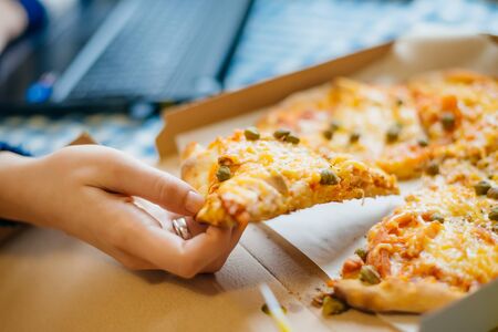 Young business woman concentrating on work and eating pizzaの写真素材