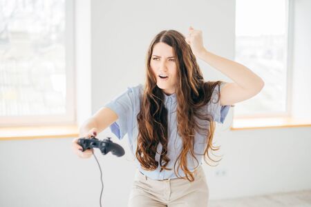 Happy woman playing video game near the window at homeの写真素材