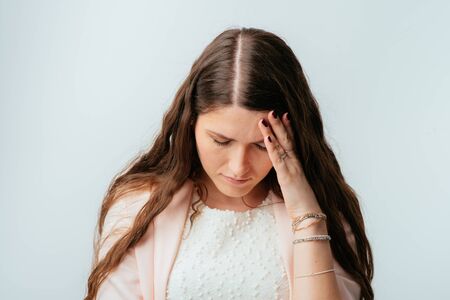 long-haired beautiful brunette girl is tired and has a headache, isolated on a white backgroundの写真素材