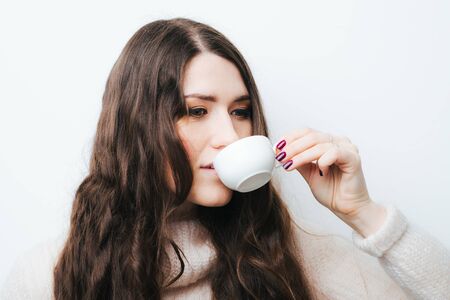 brunette girl drinking coffee or tea on a white backgroundの写真素材