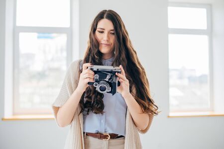 on a white background young girl with long hair with an old camera
