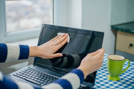 people, housework, electronics and housekeeping concept - close up of woman hand cleaning laptop...