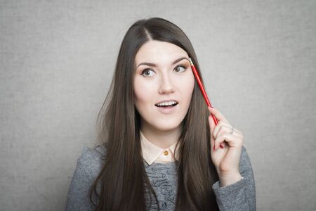 young woman holding a pencil and thinking