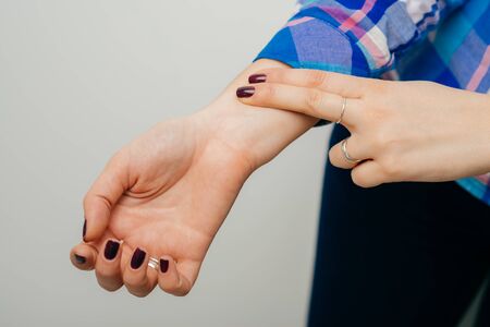 on a white background young girl checks the pulse in his handの写真素材