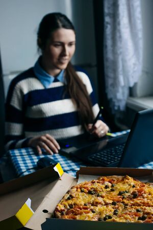 Young business woman concentrating on work and eating pizzaの写真素材