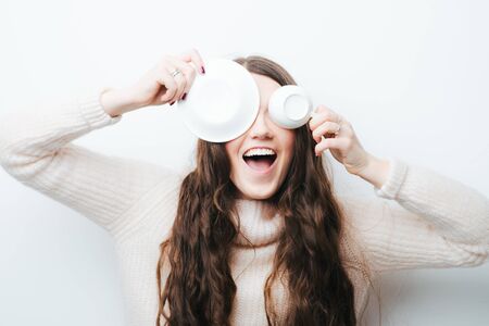 cheerful brunette girl fooling around with a cup on a white backgroundの写真素材