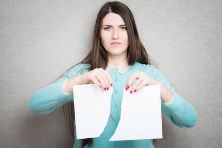 Breaking contract. Furious young woman tearing up paperの写真素材