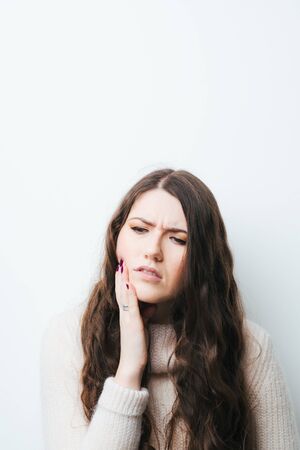 on a white background a young girl with long hair toothacheの写真素材