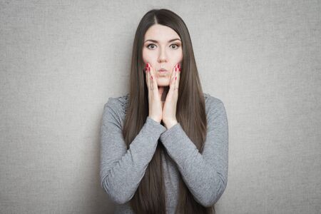 young, upset, worried, troubled brunette woman holding her head with handの写真素材