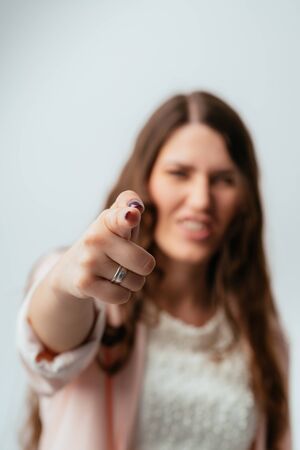long-haired beautiful brunette girl shoots a finger, isolated on a white backgroundの写真素材