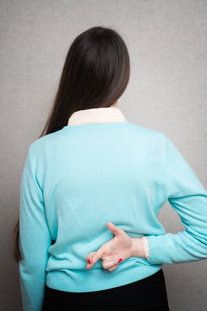 Crossed fingers behind her back as a sign of lyingの写真素材