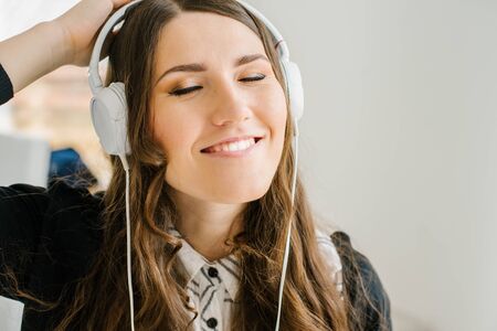 beautiful brunette girl listening to music on headphones whiteの写真素材