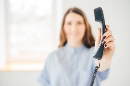 Young smiling female giving a telephone tube to someone near the window