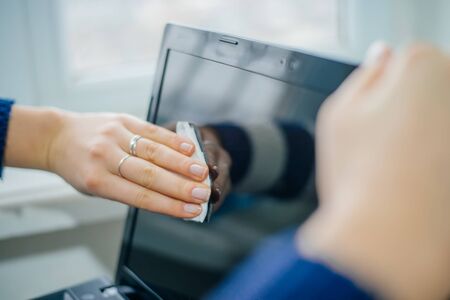 people, housework, electronics and housekeeping concept - close up of woman hand cleaning laptop computer screen with clothの写真素材