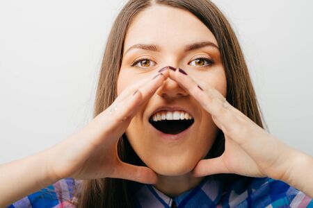 young smiling woman gesturing a verbal call against white background