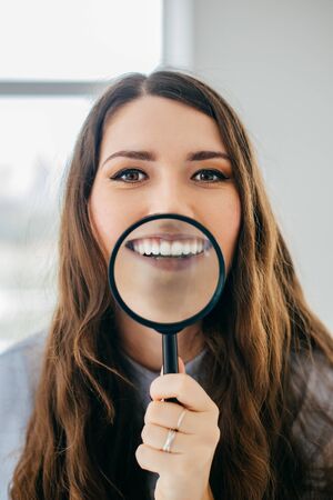 Young beautiful woman with magnifying glass near the window.の写真素材