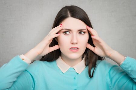 Woman suffering from an headache, holding her hands to the head