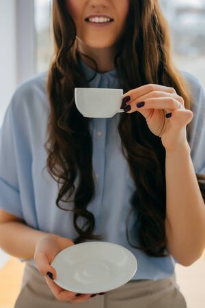 Portrait of a young woman  by window with cup of teaの写真素材