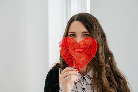 portrait of attractive  caucasian smiling woman with long curly brunette hair near the windowの写真素材