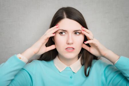 Woman suffering from an headache, holding her hands to the head