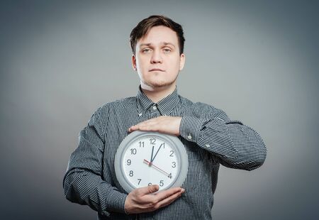 Young Man Holding A Clock On Gray Backgroundの写真素材