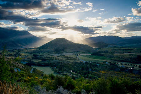 The sun sets over a lush green valley near Queenstown in New Zealandの写真素材