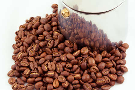 A pile of beans sit next to an Espresso makerの写真素材