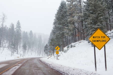 A snowy mountain road with warning signs in Cloudcroft, New Mexico, USAの写真素材