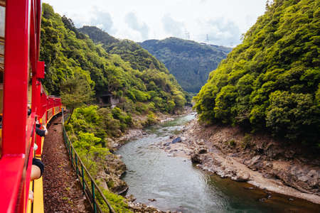 The world famous Sagano Romantic Train running along the Katsura River near Kyoto, Japanの写真素材