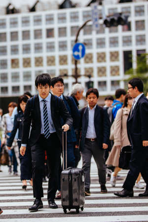 TOKYO, JAPAN - MAY 13, 2019 - A man rushes across Shibuya Crossing which is one of the world's most used pedestrian crossings, in central Tokyo, Japanのeditorial素材