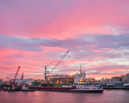 Loading operations during colourful morning in a sea harbour with barges and cranesの写真素材