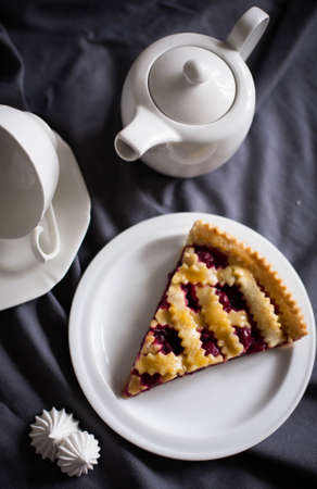 Big slice of cherry pie on a plate with teapotの写真素材