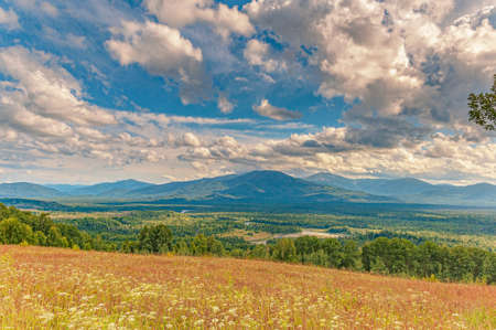 Majestic panorama of a wide mountain valley covered with taiga through which the channal of Siberian...