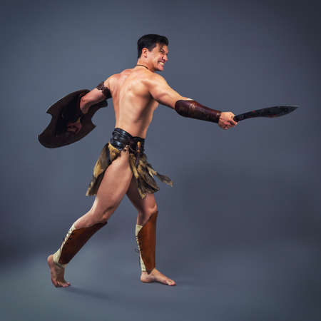 Muscular  man in the image of ancient warrior strikes with melee weaponsの写真素材
