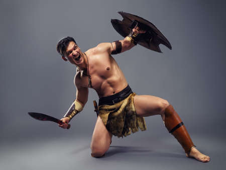 Muscular  man in the image of ancient warrior on a gray backgroundの写真素材