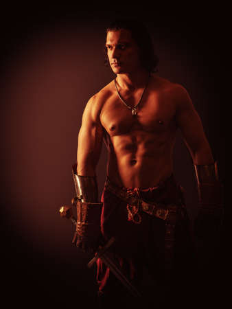 half-naked man with a sword in medieval clothes on a dark backgroundの写真素材