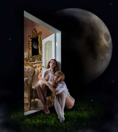 Two young girls sit on the threshold of the door between the rooms with real objects and the world with natural night abstractの写真素材