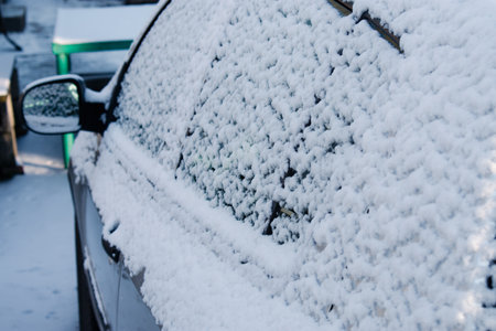 Closeup of snow covered gray car under blizzard. Cold winter, frosty snowy backgroundの写真素材