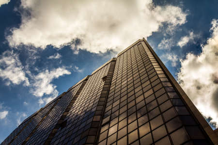 Reflective facade building with cloudy sky in financial centerの写真素材