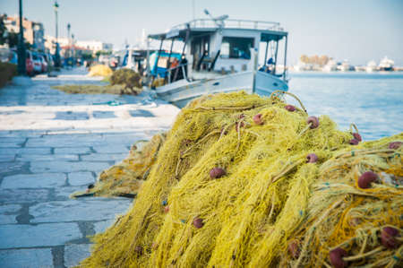 Folded fishing nets on the coast with boat in backgroundの写真素材