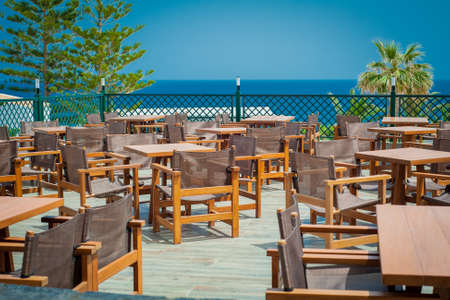 Wooden tables and chairs in seaside restaurantの写真素材